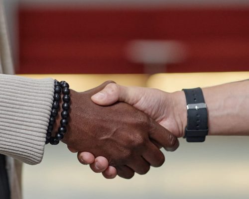 Header Image of Black Man Meeting Male Partner with Handshake in Business Center Hallway Website header shot of African American businessman shaking hands with partner making successful deal in modern office space